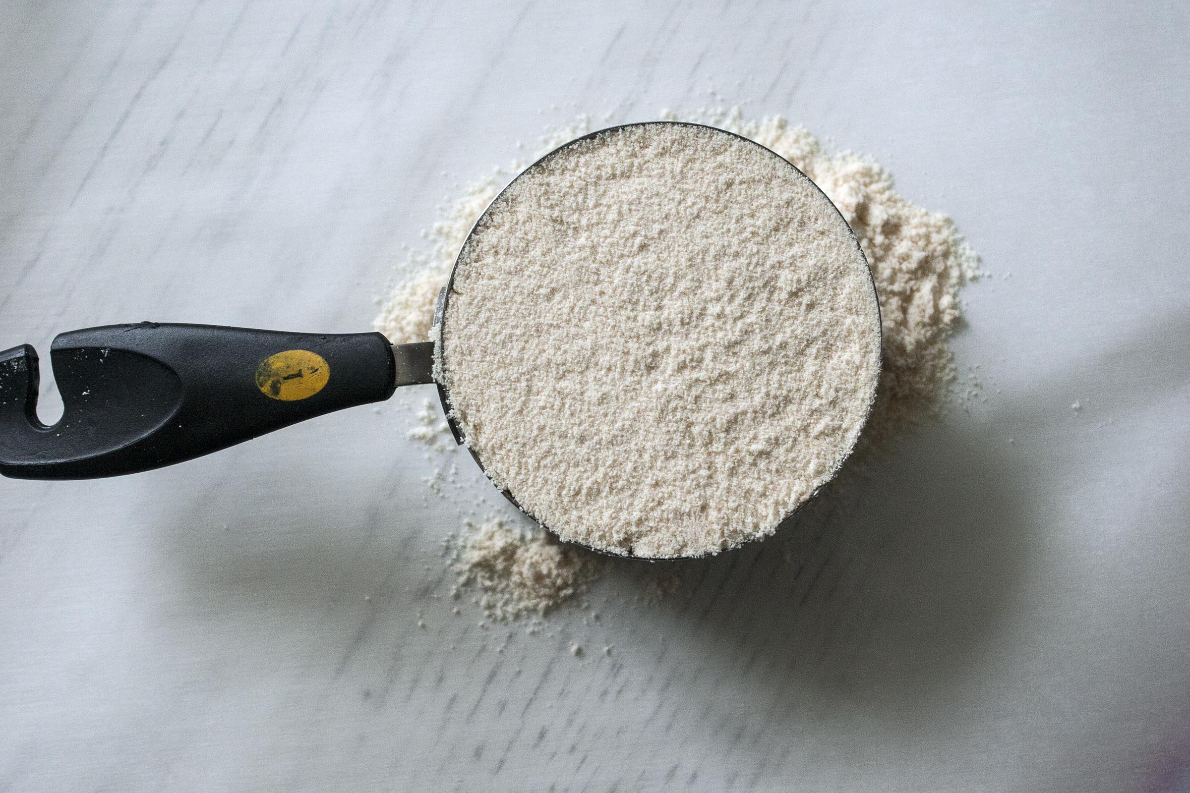 Coconut Flour measured over parchment paper for Triple Coconut Bars I lifeaswecookit.com