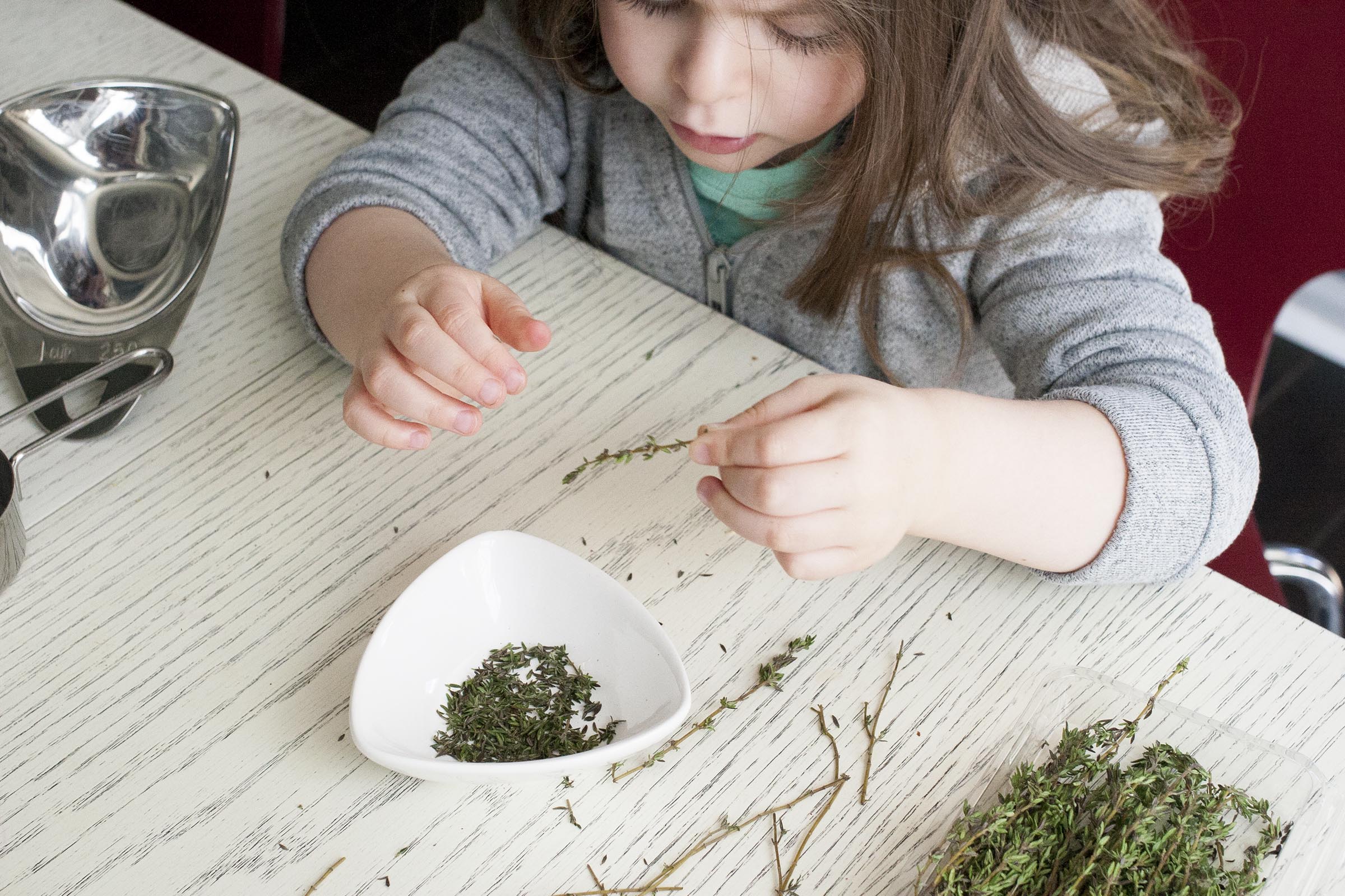 A great kid's task: plucking the leaves from a stem of thyme. www.lifeaswecookit.com