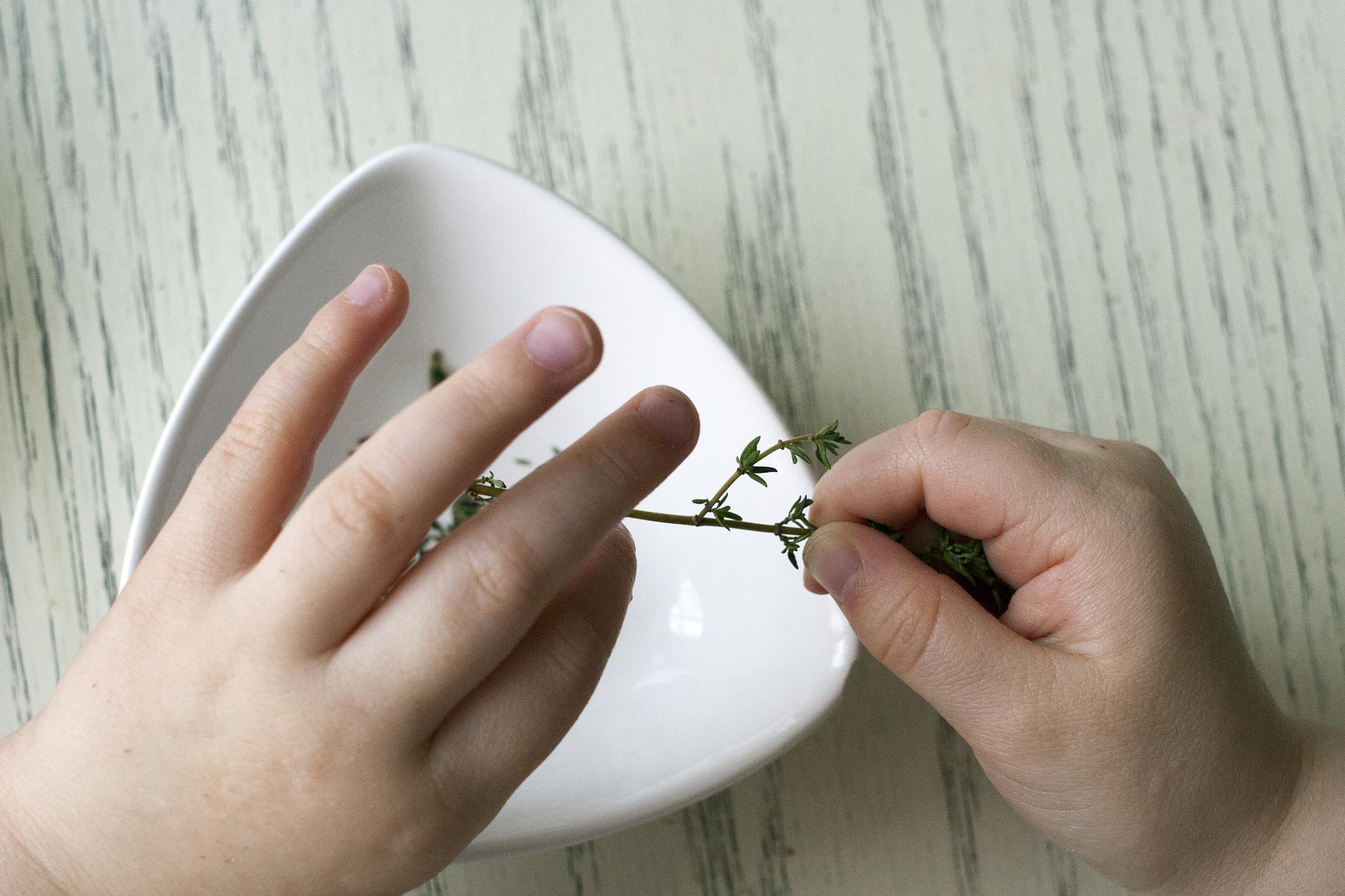 A great kid's task: plucking the leaves from a stem of thyme. www.lifeaswecookit.com